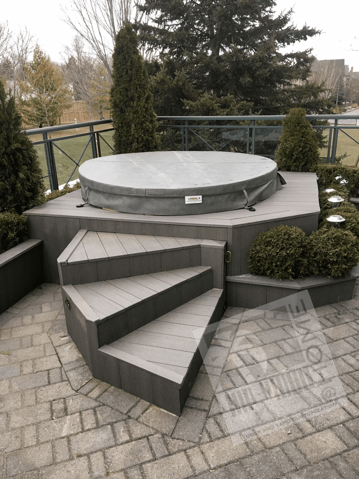Hot tub with concrete stairs and metal and glass fence